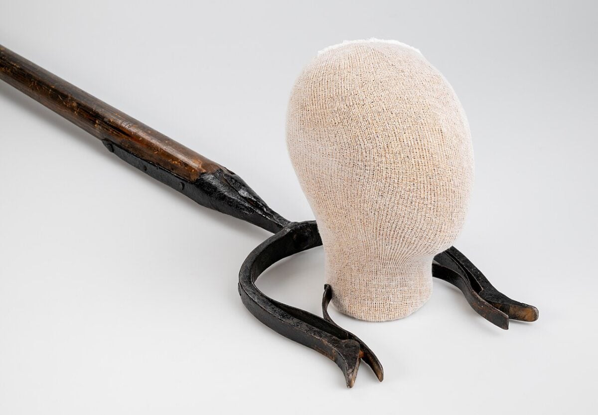 Image of a man catcher weapon next to a dummy head. 